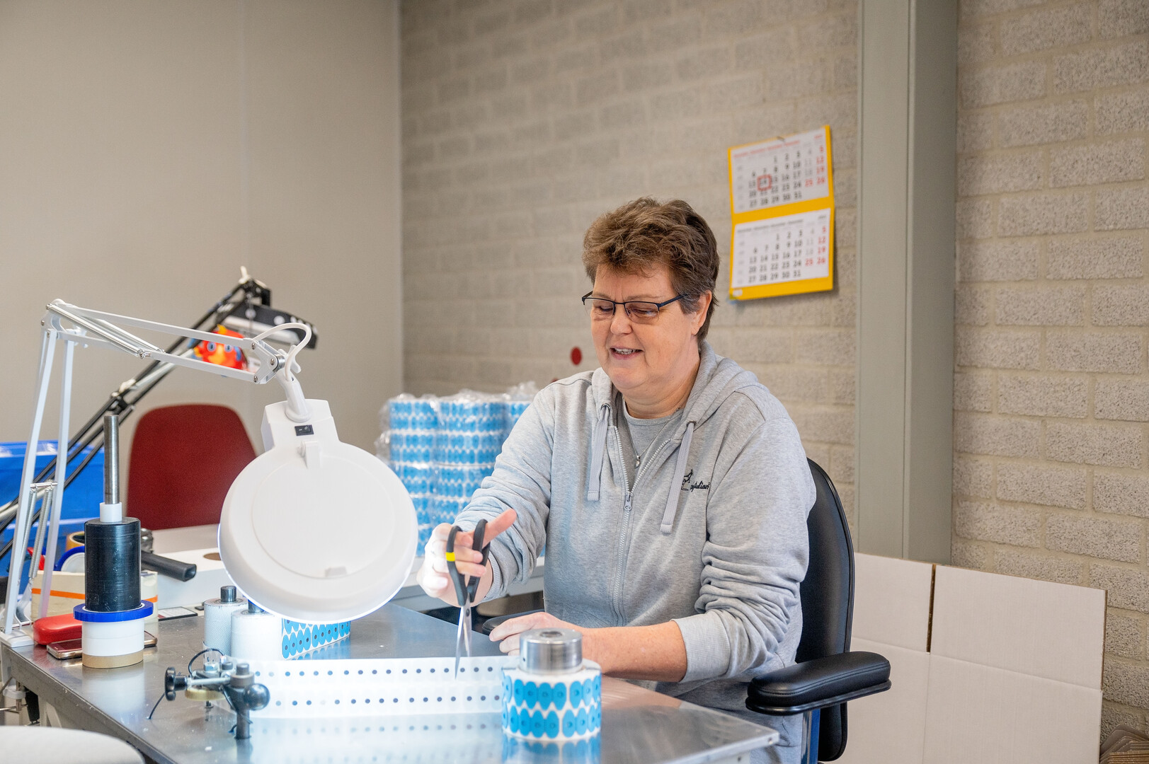 Angelique op haar werkplek met een schaar
