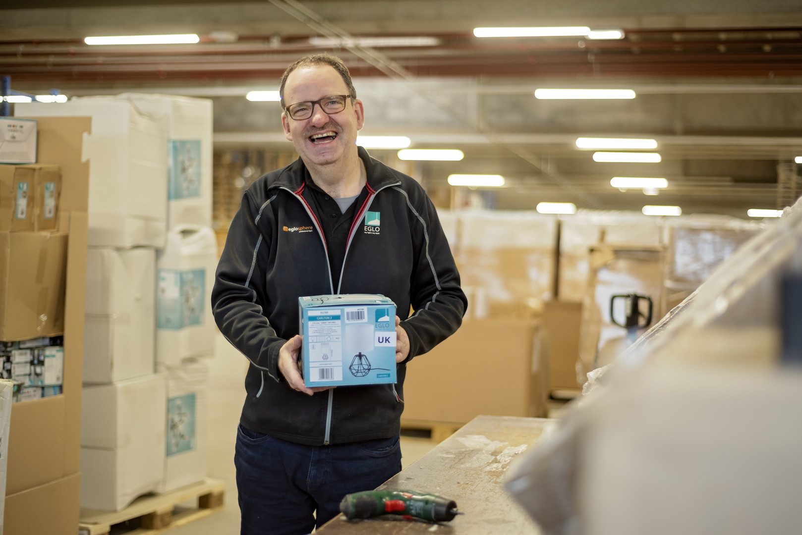 Tonny in een productiehal met een doos in zijn handen